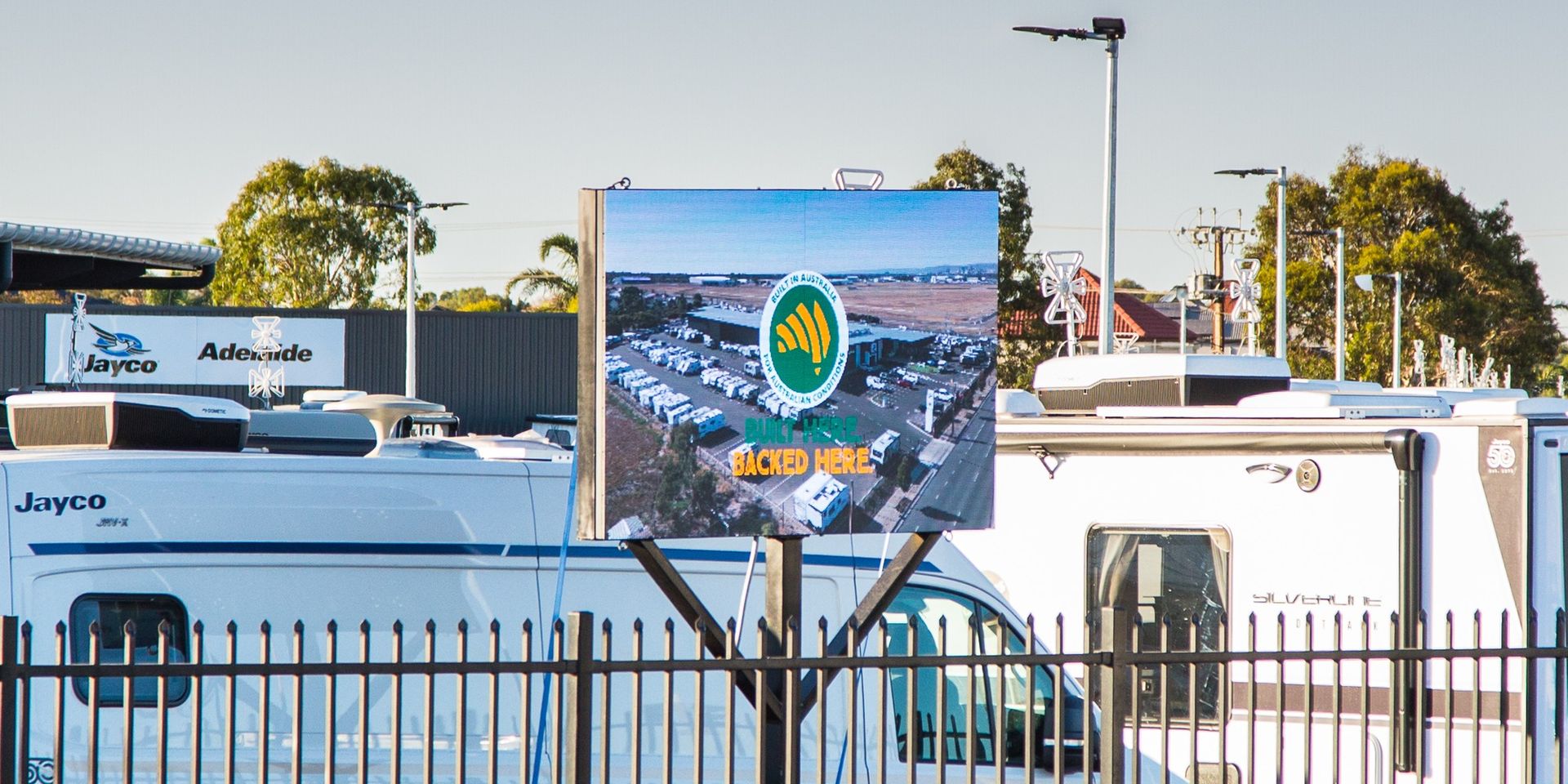 Large outdoor LED sign at Jayco Adelaide above a row of caravans